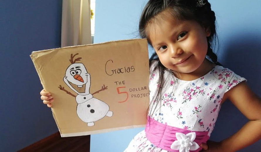 A young girl shows a sign of thanks to the Five Dollar Project.