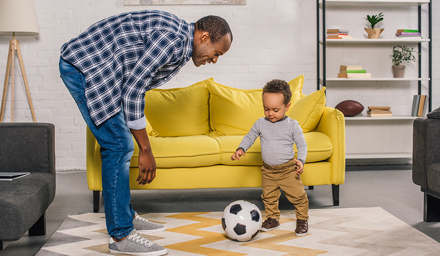  Un padre y su hijo practican fútbol dentro de la casa.