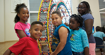 African-American children build a mini ferris wheel during summer camp. 